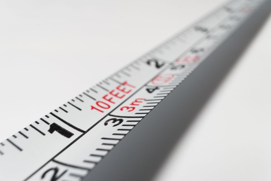 Measuring rulers marked in both feet and metres laid on a plain surface