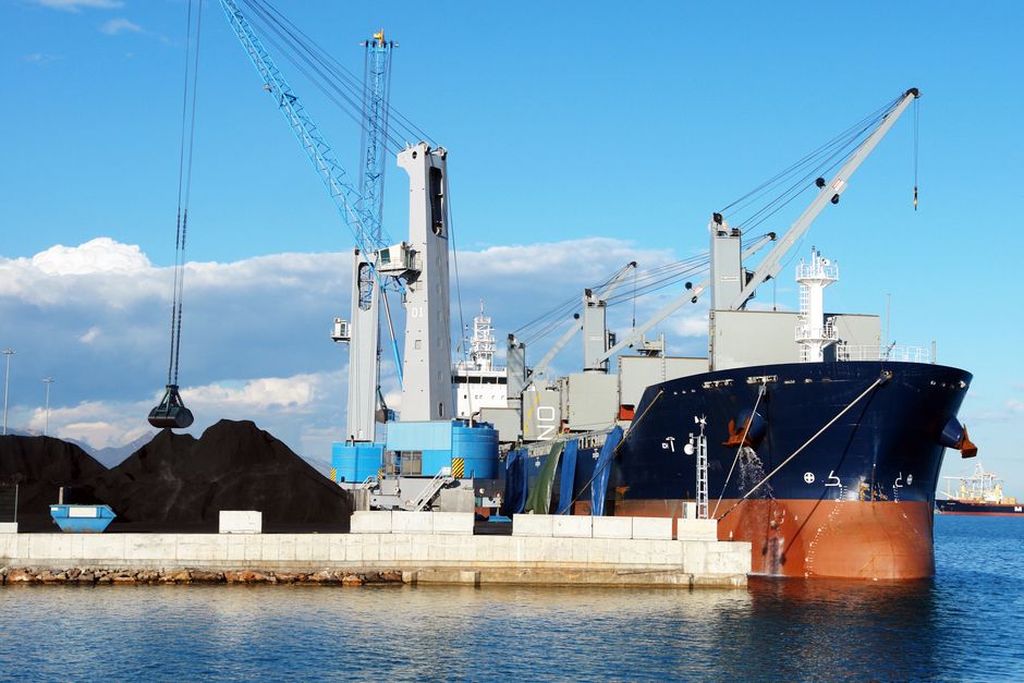 Grab crane loading coal onto a geared bulk carrier at an export quay