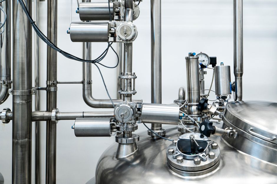 The head of a stainless process vessel, with sanitary fittings and a pressure gauge