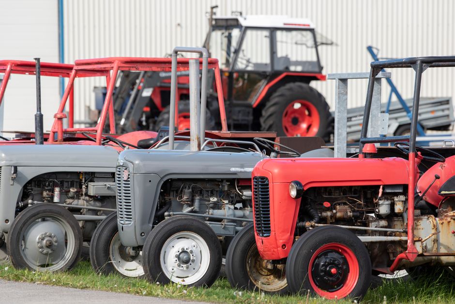 Compact tractors parked in rows beside a shed