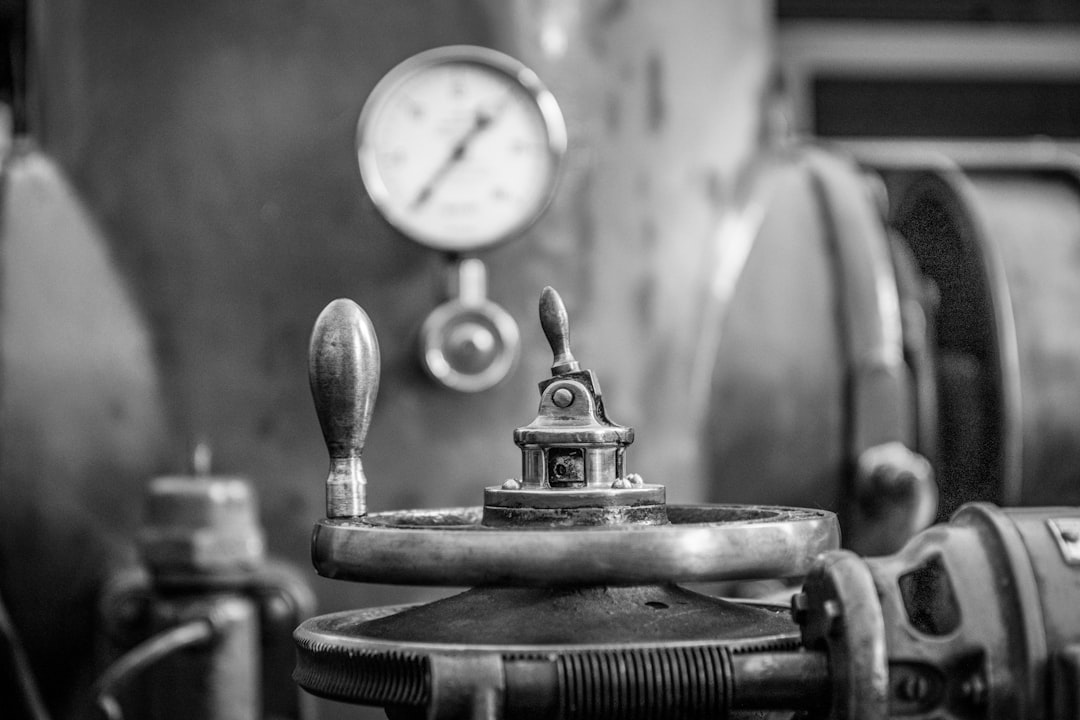 Close-up of industrial valve hardware: a handwheel, a pressure gauge and a lever on a machine body