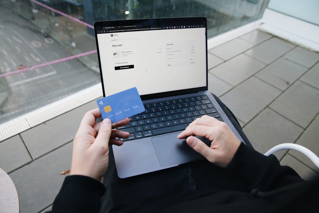 A card held over a laptop checkout screen, a reference photograph for this payments analysis