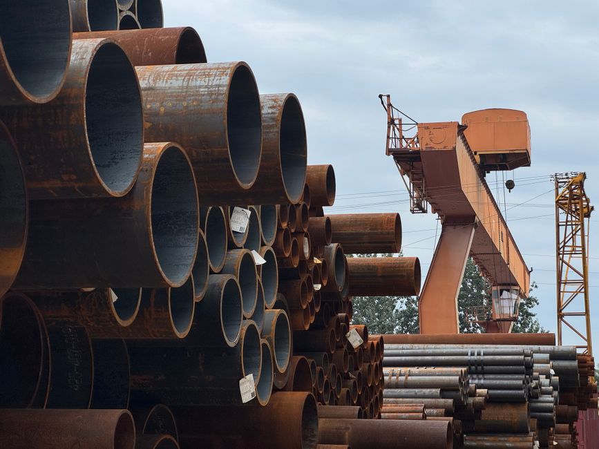 Rows of large metal water pipes stacked in an outdoor yard