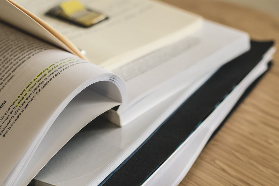Printed report pages stacked on a wooden desk, illustrating SM Entertainment stock analysis